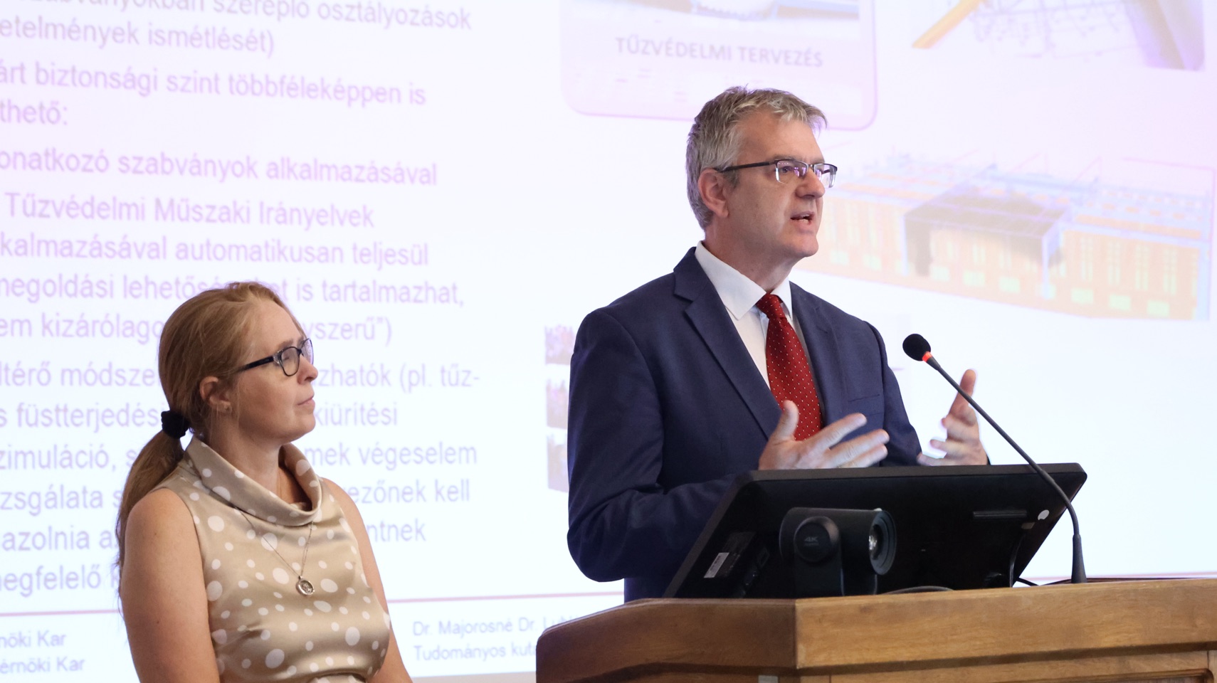 Két előadó tűzvédelmi tervezési témájú prezentáció közben.